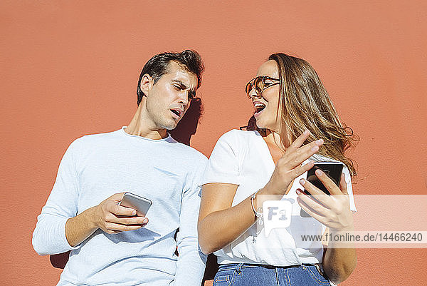 Paar mit Mobiltelefonen an einem sonnigen Tag im Freien