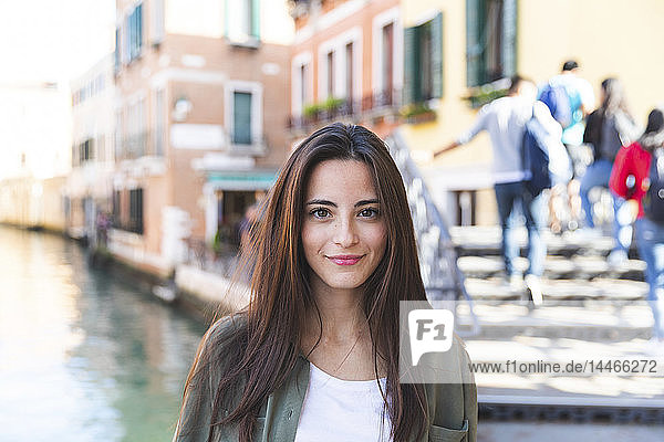Italien  Venedig  Porträt einer lächelnden jungen Frau in der Stadt mit Kanal im Hintergrund