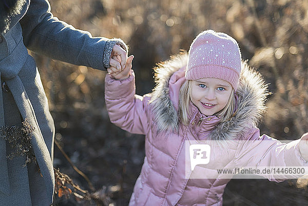 Portrait of little girl hand in hand with her mother on autumnal meadow at Golden hour