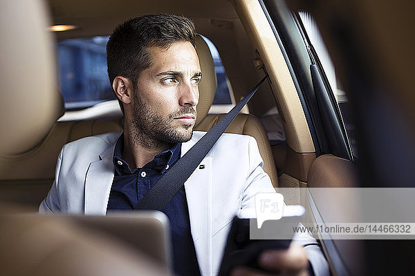 Young businessman sitting in car  using smartphone