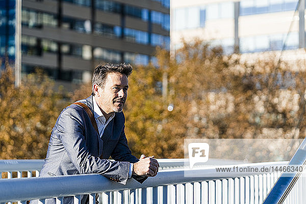 Relaxed businessman leaning on a railing  taking a break