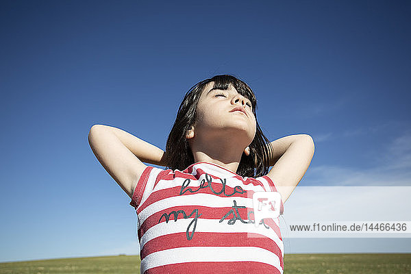 Mädchen mit geschlossenen Augen genießt Sonnenschein in entlegener Landschaft
