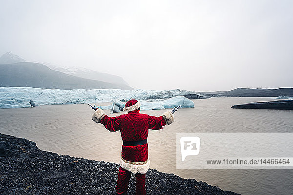 Island  Rückenansicht des vor dem Gletscher stehenden Weihnachtsmanns