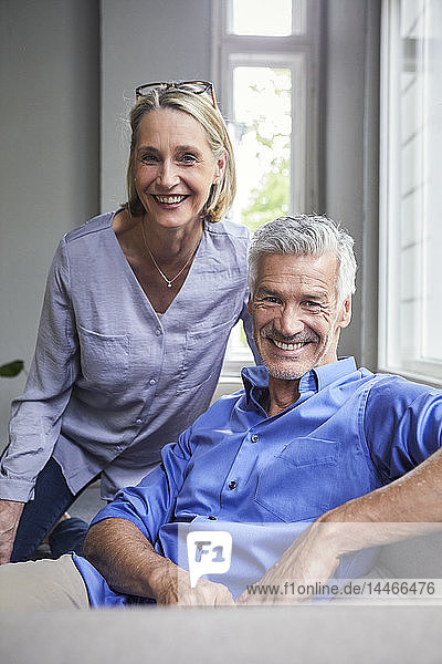 Portrait of smiling mature couple on couch at home