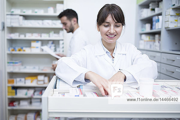 Lächelnder Apotheker sucht Medizin am Kabinett in der Apotheke
