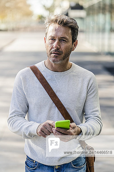 Mature man commuiting in the city  holding smartphone
