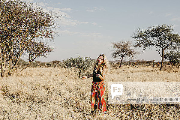 Africa  Namibia  blonde smiling woman standing in grassland