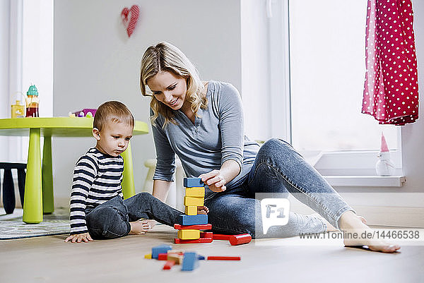 Lächelnde Mutter und Kleinkind spielen zu Hause mit Bausteinen