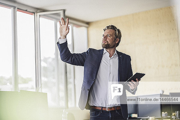 Businessman standing in office  holding digital talet  using his imagination