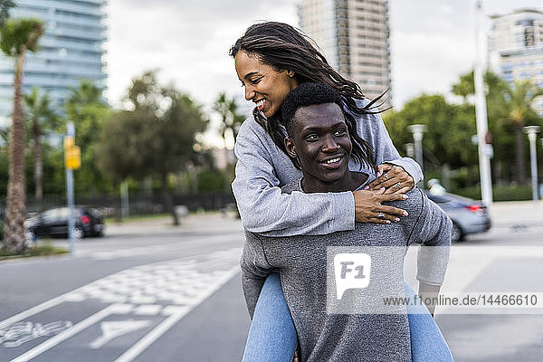 Young man carrying his girlfriend piggyback in the street