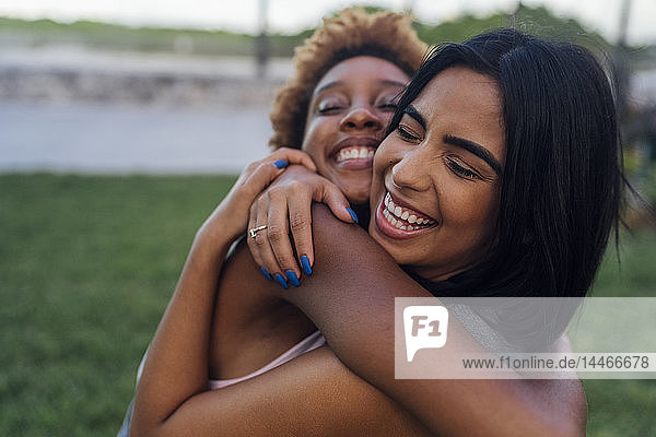 Porträt von zwei glücklichen Freundinnen  die sich in einem Park umarmen