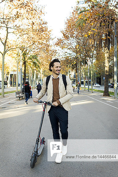 Lächelnder Mann mit Rucksack E-Scooter in der Stadt