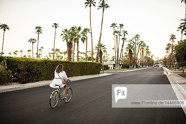USA  Kalifornien  Palm Springs  Fahrrad fahrende Frau auf der Straße