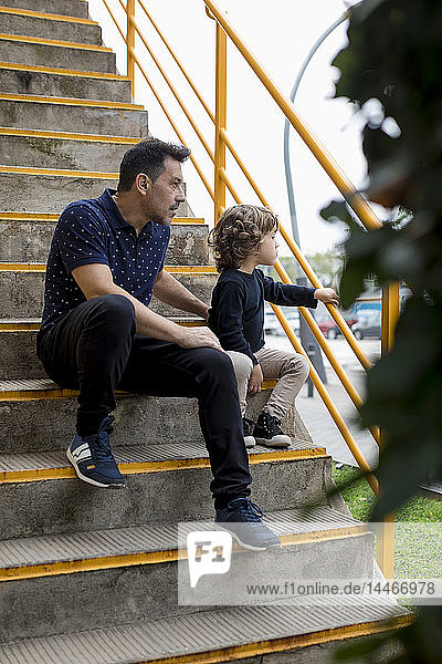 Vater und Sohn sitzen auf einer Treppe in der Stadt