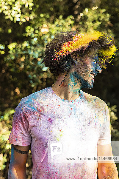 Mann schüttelt den Kopf  voll bunter Pulverfarbe  feiert Holi  das Fest der Farben