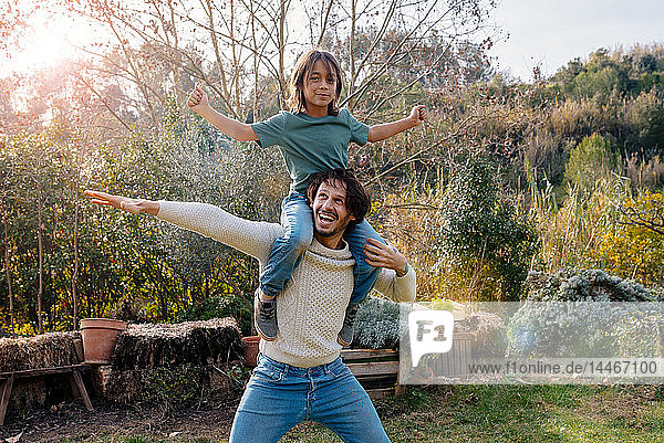 Father carrying son piggyback in a garden in the countryside