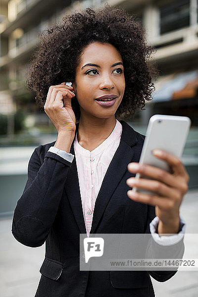 Porträt einer lächelnden Nutzfrau mit Smartphone und Kopfhörern