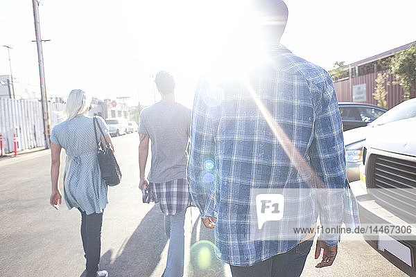 Three young people walking on the street in sunshine