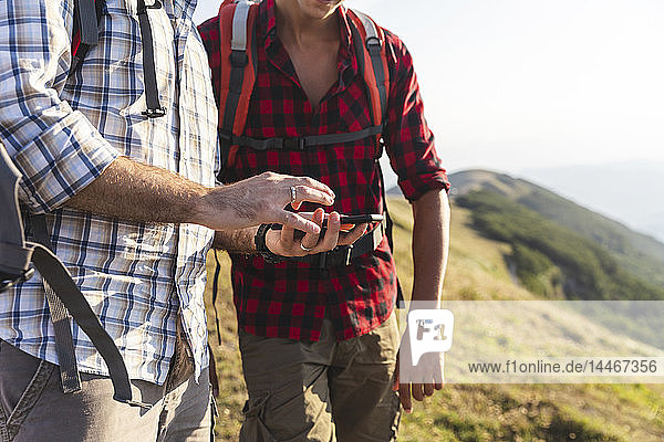 Italien  Monte Nerone  Nahaufnahme von zwei Männern  die in den Bergen wandern und ihr Smartphone benutzen