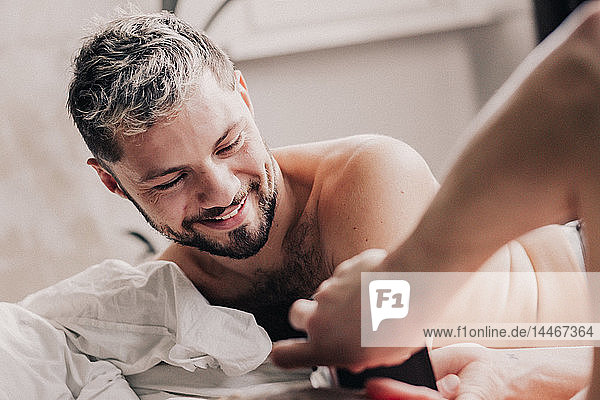 Porträt eines lächelnden schwulen Mannes mit seiner Partnerin im Bett