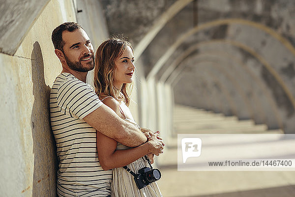 Spanien  Andalusien  Malaga  liebevolles Touristenpaar  das sich unter einem Torbogen in der Stadt umarmt