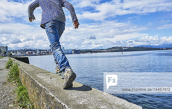 Chile  Puerto Montt  Junge rennt auf Kaimauer am Hafen