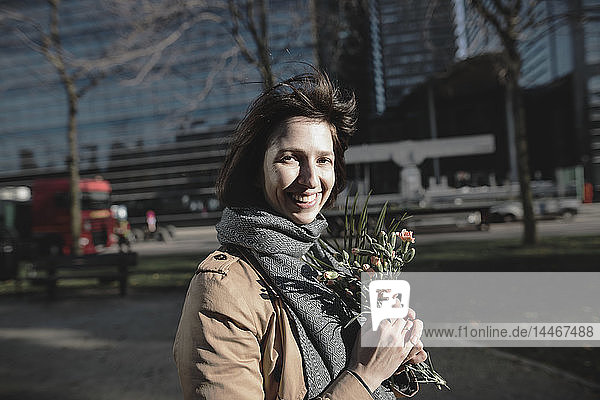 Porträt einer lächelnden Frau mit Blumenstrauss in der Stadt