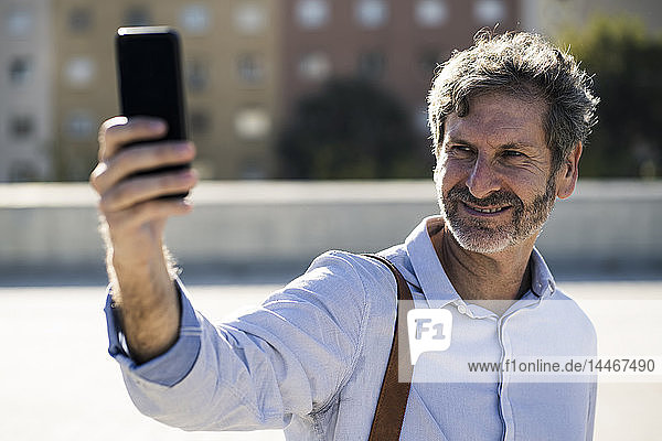 Lächelnder reifer Mann  der in der Stadt ein Selfie macht