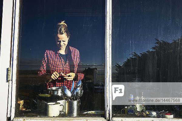 Frau hinter Küchenfenster beim Zubereiten der Mahlzeit