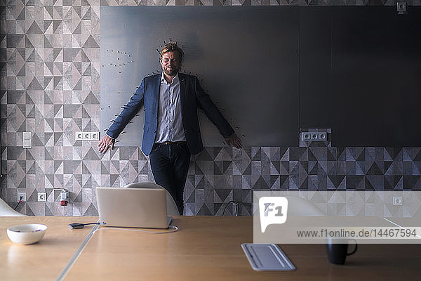 Businessman standiing in boardroom with back to a magnet wall  framed by arrows