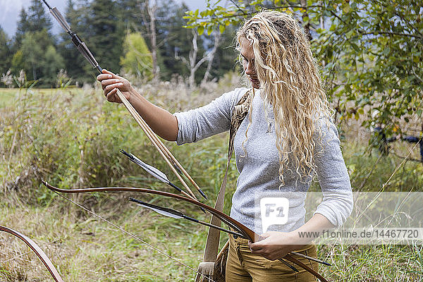 Archeress sorting bow and arrows in nature
