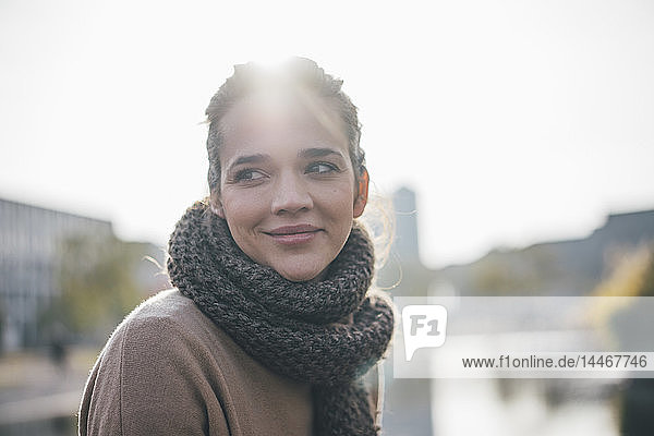 Porträt einer lächelnden Frau mit Schal im Gegenlicht