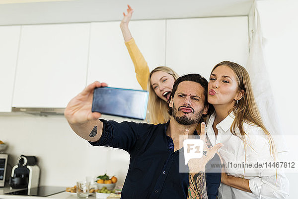 Freunde haben Spaß daran  in der Küche zu stehen und mit ihren Smartphones Fotos zu machen