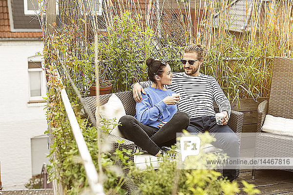 Junges Paar entspannt sich auf dem Balkon  auf der Couch sitzend