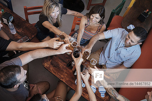 Freunde beim geselligen Beisammensein und klirrenden Biergläsern in einer Bar