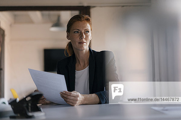 Businesswoman holding paper at desk in office
