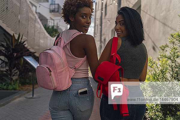 USA  Florida  Miami Beach  Rückansicht von zwei glücklichen Freundinnen  die in der Stadt spazieren