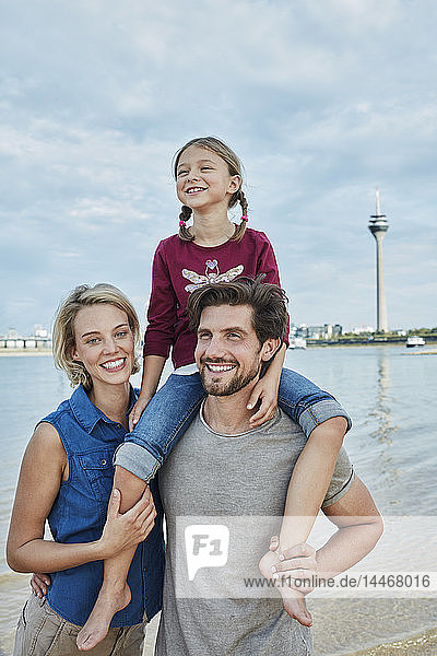 Germany  Duesseldorf  happy family with daughter at Rhine riverbank