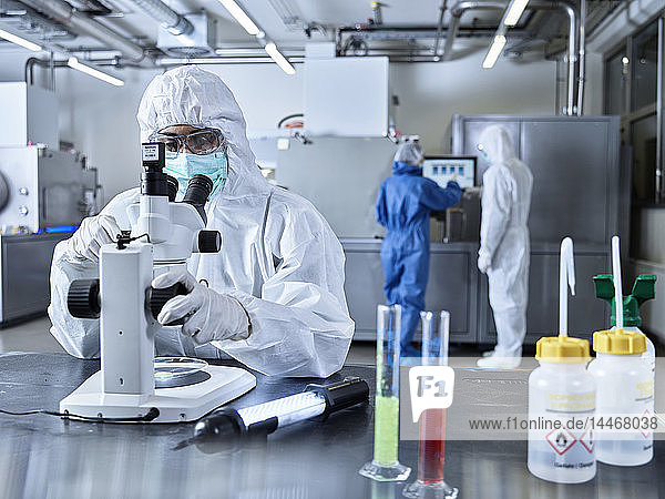Chemiker  die im Industrielabor arbeiten  Schutzkleidung tragen  Mikroskop benutzen