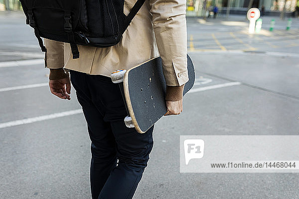 Mann mit Rucksack und Skateboard in der Stadt  Teilansicht
