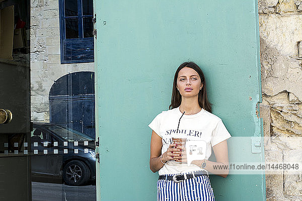 Porträt einer jungen Frau mit Papierbecher Eiskaffee
