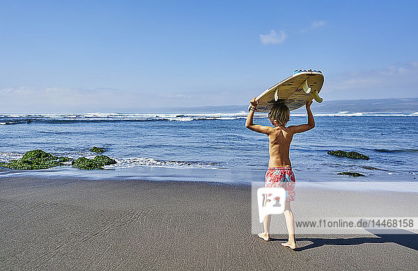 Chile Pichilemu Junge mit Surfbrett auf dem Meer