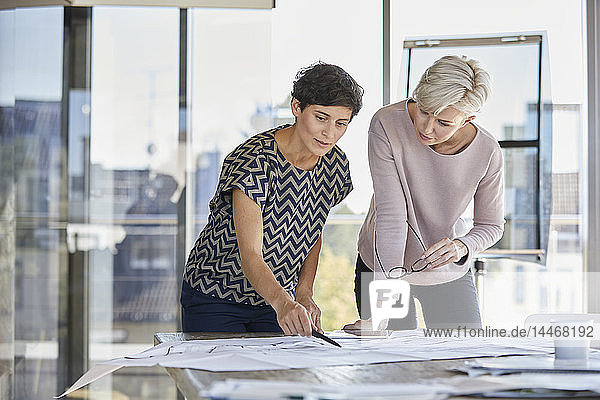 Zwei Geschäftsfrauen besprechen den Grundriss auf dem Schreibtisch im Büro