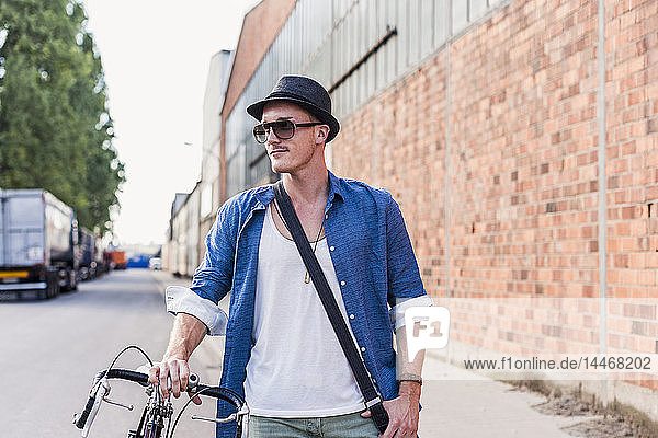 Junger Mann mit Fahrrad auf der Straße