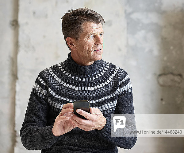 Man wearing pullover holding cell phone