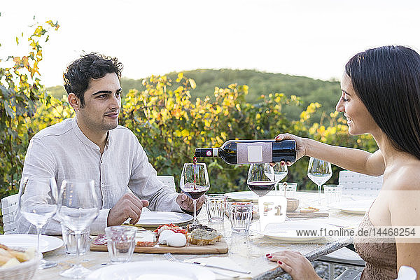 Italien  Toskana  Siena  junges Paar beim Abendessen in einem Weinberg mit Rotwein