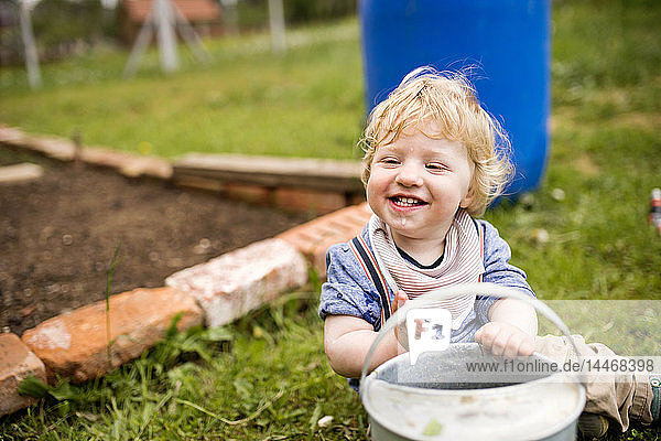 Junge im Garten spielt mit Gießkanne