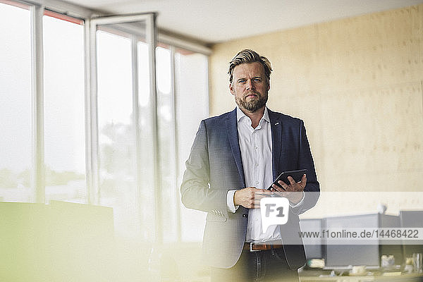 Businessman standing in office  using digital talet