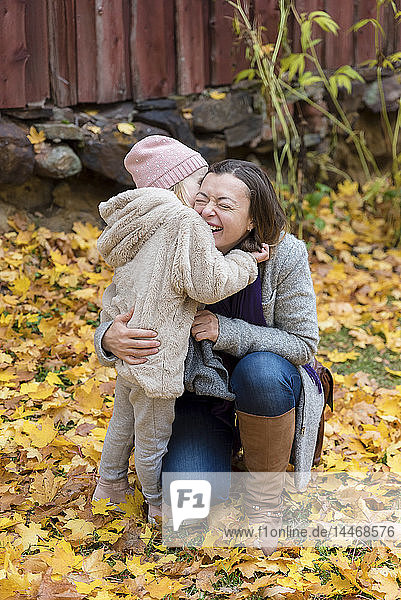 Finnland  Kuopio  Mutter und kleine Tochter kuscheln im Herbst zusammen