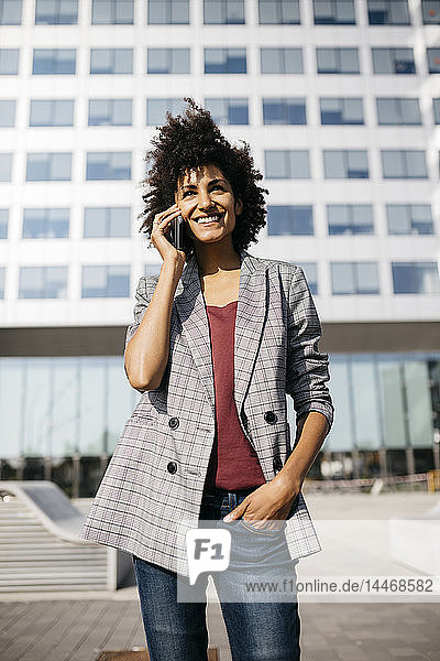 Lächelnde Geschäftsfrau am Handy vor dem Bürogebäude